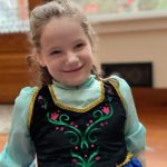 A photo of a smiling young girl in a dress.