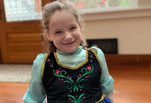 A photo of a smiling young girl in a dress.